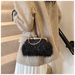 Détail d'un sac de soirée élégant à plumes noires avec chaîne dorée et fermoir coquille
