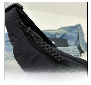 Macro view of a smooth zipper with woven puller on a black crescent-shaped bag