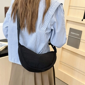 Borsa a tracolla a mezzaluna in tela nera minimalista indossata da una modella in interno