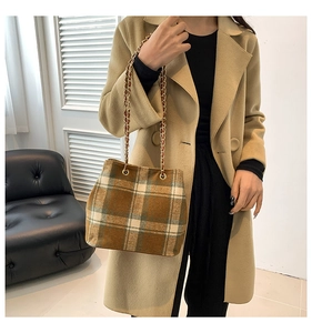 Close-up of retro plaid bucket bag featuring textured wool and gold chain strap detail