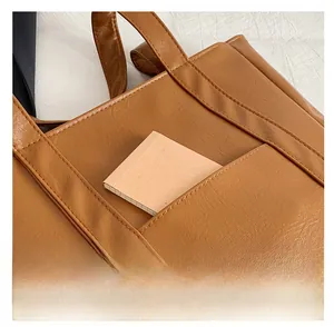 Detail view of the brown leather tote bag front pocket with a stylish notebook insert