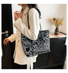 Detail of large black graffiti tote bag with white cartoon prints and long shoulder straps
