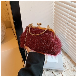 Macro shot of burgundy tassel clutch featuring a golden metal handle and fine chain strap