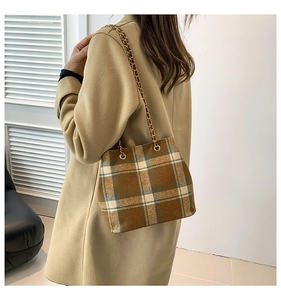 Detail of wool plaid shoulder bag with golden chain strap on a model's beige coat
