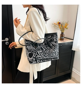 Detail of a large capacity graffiti tote bag worn with an elegant cream blazer