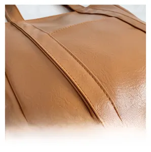 Macro shot of brown leather tote showing detailed lychee grain and uniform double stitching