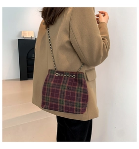 Détail du sac seau en laine à carreaux rouge et vert avec cordon en chaîne dorée