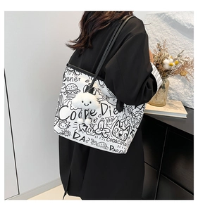 Macro detail of white graffiti tote bag with plush charm and black shoulder strap