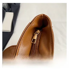 Detail view of smooth metal zipper and textured brown leather on this retro tote bag