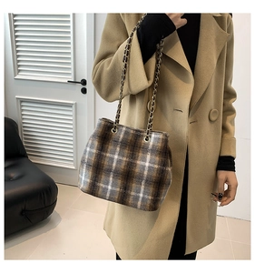Detail of wool bucket bag with gold chain strap on camel coat for autumn fashion