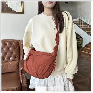 Detail of rust red nylon crescent crossbody bag with adjustable strap and textured fabric