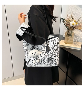 Detail of white tote bag with black cartoon graffiti and plush cloud charm accessory