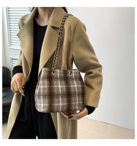 Detail of vintage plaid wool tote bag with golden chain strap on a khaki coat