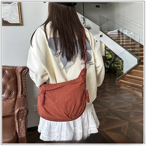 Model wearing a large rust red crescent crossbody bag in a stylish indoor setting