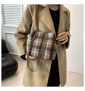Detail of vintage plaid bucket bag with gold chain straps on camel coat