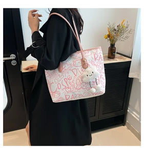 Detail of white graffiti canvas tote bag with pink straps and a plush cloud charm