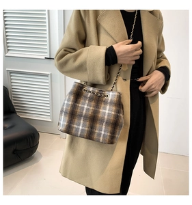 Detail of vintage plaid bucket bag featuring a golden chain strap and textured wool fabric