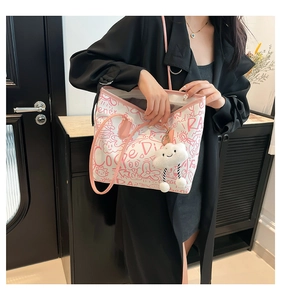 Close-up of graffiti tote bag with pink leather handles and cute plush cloud charm