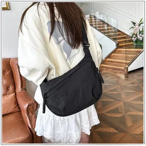 Close-up of black nylon crescent bag worn crossbody, showing wide adjustable strap details