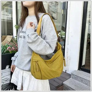 Outdoor shot of a mustard yellow crescent bag featuring woven rope knot details