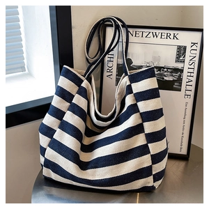 Detail of a large striped canvas tote bag in navy and cream on a metallic surface