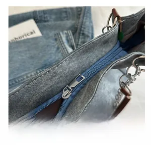 Detail of silver zipper closure and pearl chain on light blue washed denim tote bag