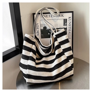 Close-up of black and white striped canvas tote bag on a modern metal table