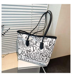 Detail of white tote bag featuring black graffiti prints and long black shoulder straps