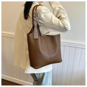 Close-up of brown pebbled leather tote bag featuring fashion silk scarf on handle