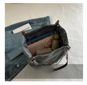 Internal capacity of denim tote bag showing umbrella, wallet, and pearl chain detail