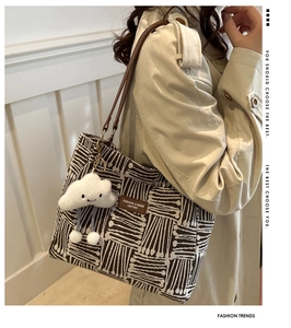Detail of striped canvas tote bag with leather straps and cloud plush pendant accessory