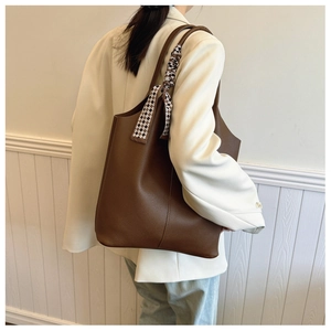 Detail of brown litchi pattern leather tote bag with black and white checkered ribbon