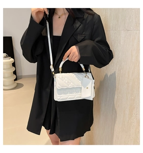Detail of white quilted crossbody bag with woven handle and small coin purse attachment
