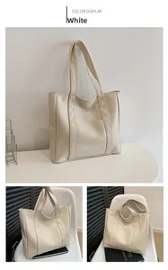 Close-up of a white minimalist tote bag showing textured faux leather and front pocket detail