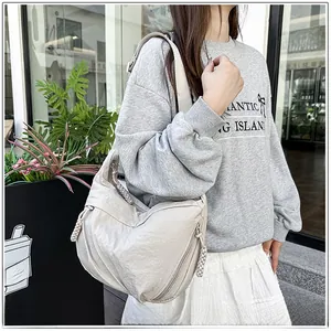 Detail of cream hobo bag featuring thick woven rope zipper pull and textured fabric
