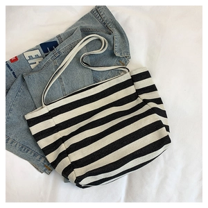 Flat lay of a striped canvas tote bag with shoulder straps on blue denim jacket background