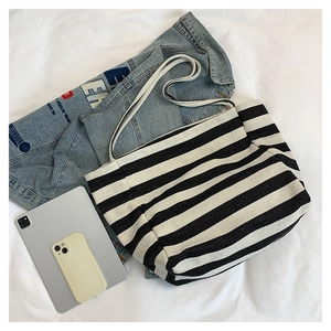 Striped canvas tote bag detail showing woven texture with denim jacket and tablet