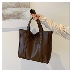 Detail of a dark brown large-capacity tote bag with vertical stitching and textured finish