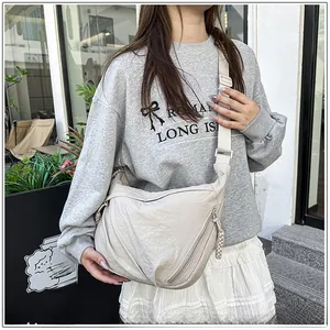 Detail of beige crescent crossbody bag with pleated nylon fabric and woven zipper puller
