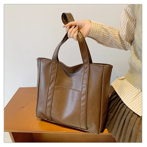 Detail of dark brown tote bag in crinkled PU leather with front pocket and double handles