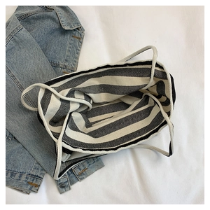Top view of striped canvas tote bag with cotton rope handles on a denim jacket background