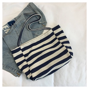 Detail view of large striped canvas tote bag paired with denim jacket for casual style