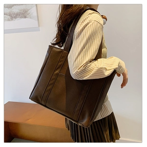 Close-up of a large coffee brown faux leather tote bag with vertical stitching