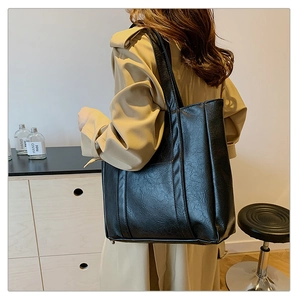 Detail of black large capacity tote bag with embossed PU leather texture on shoulder