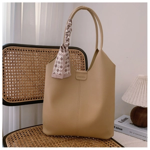 Detail of khaki tote bag with litchi texture, fashion label and decorative silk scarf
