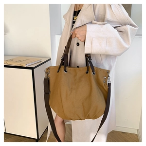 Detail of earthy brown canvas tote bag featuring durable handles and adjustable shoulder strap