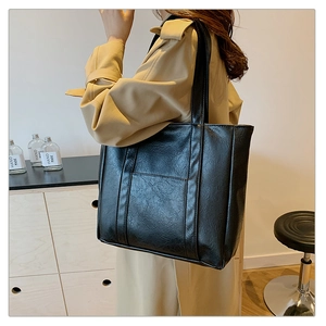 Close-up of black vintage tote bag in textured PU leather with vertical stitching detail