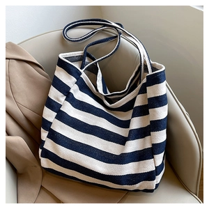 Detailed texture of durable blue and white striped canvas tote bag on a leather seat