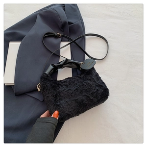 Detail of plush black faux fur handbag with leather-like handle and golden hardware accent