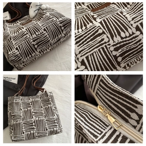 Detail of striped woven tote bag with brown leather straps and gold zipper closure